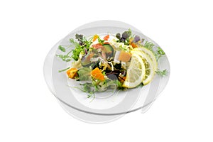 Vegetable salad with greens and pumpkin on a white plate on an isolated background, bright summer vegetables