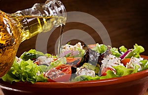 Vegetable salad with olive oil pouring from a bott