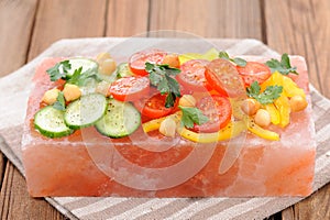 Vegetable salad on pink salt block on stripe napkin