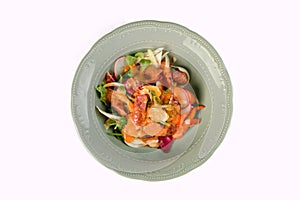 Vegetable salad with sausages in a plate on an isolated background