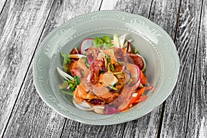 Vegetable salad with sausages in a plate on an isolated background