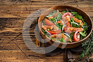 Vegetable salad with smoked salmon, arugula, tomato and green vegetables. wooden background. Top View. Copy space