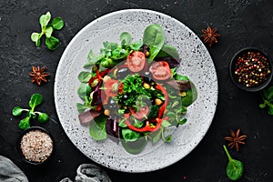 Vegetable salad with spinach, tomatoes, paprika and pumpkin seeds in a plate on a wooden background Top view. Free space for your