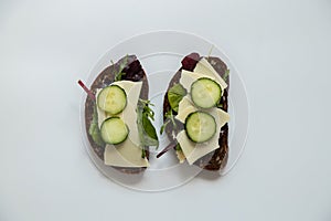 Vegetable sandwich with cheese and cucumbers and black bread with seeds on a white background, quick lunch, food