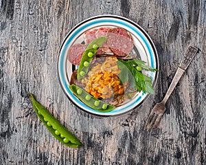 Vegetable snacks and slices of sausage on a ceramic plate and fresh herbs