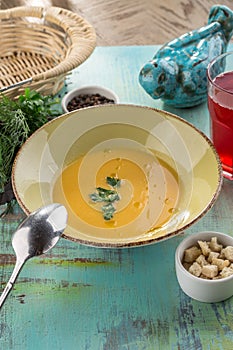Vegetable soup with cream and pumpkin and croutons and glass of red drink on blue wooden table