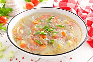 Vegetable soup. Healthy food, vegetarian dish. Vegetable soup with cabbage, potato, tomato, carrot, celery, pepper and green peas.