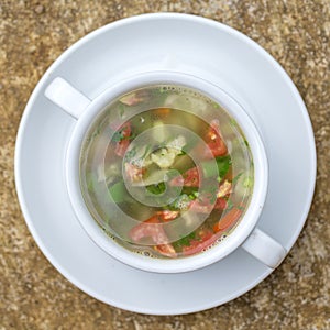 Vegetable soup with ingredients cauliflower, red tomato, green beans in white plate, top view