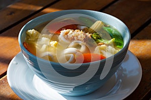 Vegetable soup with noodles on a wooden table