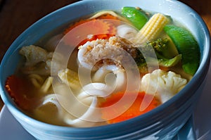 Vegetable soup with noodles on a wooden table