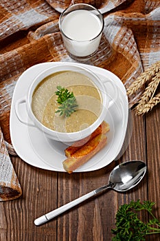 Vegetable soup with parsley and fried bread on a wooden table.