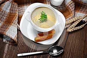 Vegetable soup with parsley and fried bread on a wooden table.