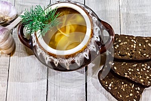 Vegetable soup in a pot with bread and fresh garlic on a gray wooden background