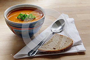 Vegetable soup in a pottery bowl, bread and spoon