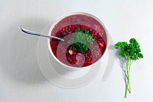 Vegetable soup - red borsch in a white bowl on a white wooden background, top view. Healthy beetroot soup, vegetarian food..