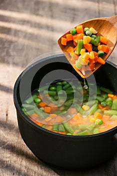 Vegetable stew in gray pot on color napkin on wooden background