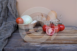 Vegetable stocks are laid out on wooden shelf, ripe red tomatoes, head of cabbage in basket, garlic, pumpkin, onions, old dishes,