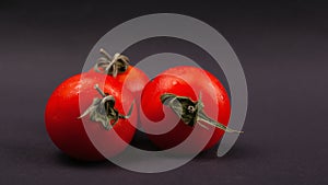 Vegetable, three cherry tomatoes on a dark background close-up