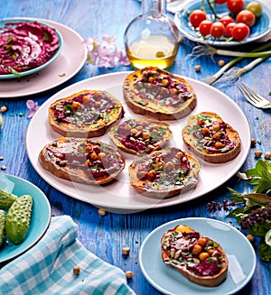 Sweet potato toast with beet hummus, grilled chickpeas, fresh parsley, nigella seeds and sunflower seeds on a plate on a table