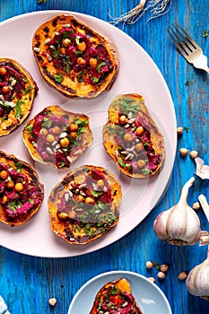 Sweet potato toast with beet hummus, grilled chickpeas, fresh parsley, nigella seeds and sunflower seeds on a plate on a table