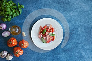 Vegetable tomato salad with extra virgin olive oil, purple onion, purple garlic and basil. Accompanied by a bottle of extra virgin photo