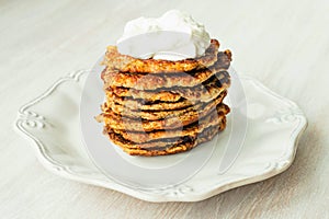 Vegetable Zucchini fritters stack served sour cream on on white plate close up