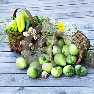 Vegetables in a basket and a bouquet of wild flowers on a wooden background. Wicker baskets are filled with fresh vegetables and