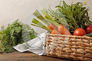 Vegetables in a basket. Carrots, tomatoes and cucumbers with herbs in a straw box.