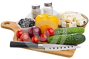 Vegetables, black olives, cheese and condiments for preparation greek salad, knife on cutting board isolated on white