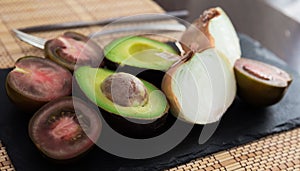 vegetables black tomatoes, avocado and onions on black stone board