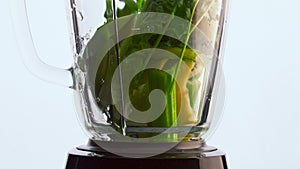 Vegetables blender poured water close up. Organic veggies fruits herbs in mixer.