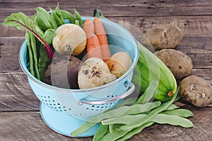 Vegetables with blue drainer on wooden background.