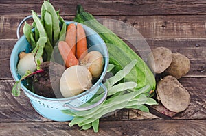 Vegetables with blue drainer on wooden background.
