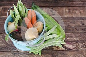 Vegetables with blue drainer on wooden background.