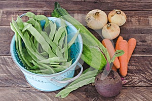 Vegetables with blue drainer on wooden background.