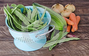 Vegetables with blue drainer on wooden background.