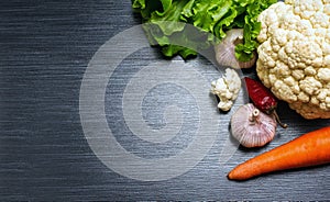 Vegetables close-up. Cauliflower, garlics, carrot, lettuce and red pepper on a wooden table. Top v