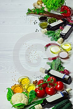 Vegetables, different kinds of unrefined oil, nuts  seeds on a white wooden table