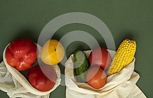 Vegetables in eco bag on green surface with a copy space. Pepper, tomato, corn, cucumber, broccoli, cauliflower in