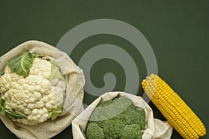 Vegetables in eco bag on green surface with a copy space. Pepper, tomato, corn, cucumber, broccoli, cauliflower in