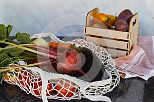 Vegetables in eco shopping reusable bag and wooden box tomatoes, purple potatoes, eggplants, carrots, sweet pepper