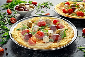 Vegetables Eggs Omelette with tomatoes, wild rocket, greek cheese, olives in a plate. Morning breakfast. healthy food