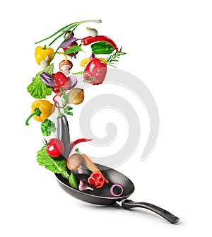 Vegetables are flying out of the pan isolated on white background. Healthy food photo