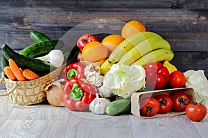 Vegetables and fruits on a graphite wooden background: in a box are tomatoes, cucumber, garlic, large red peppers, Iceberg lettuce