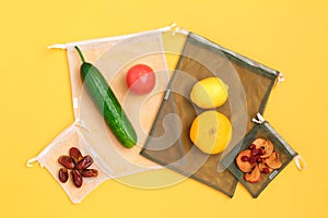 Vegetables and fruits on reusable eco friendly mesh bags on yellow background