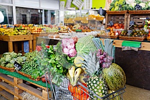 Vegetables and fruits in shopping cart in greengrocery