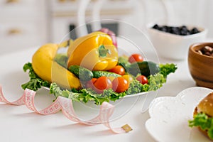 Vegetables and fruits for weight loss on a plate with a measuring tape in the kitchen
