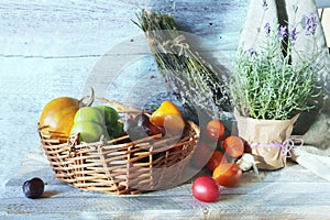 Vegetables and fruits in a wicker basket, healthy flowers and herbs on a wooden table, harvest season, organic natural food