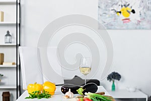 vegetables and glass of wine on kitchen counter in light