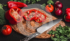 Vegetables with knife on cutting board over stone background, cooking food. Ingredients on table.